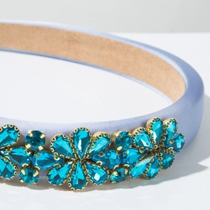 Makroansicht des blauen Kristalldetails auf einem lila Satin-Barock-Haarreif