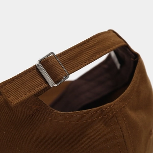 Detail of dark brown twill cotton baseball cap with adjustable silver metal buckle