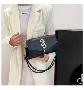 Detail of black crossbody bag featuring gold SS buckle, fringe and crocodile texture
