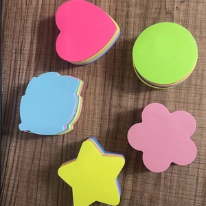 Fluorescent colorful sticky notes in heart, star, and flower shapes on a wooden desk