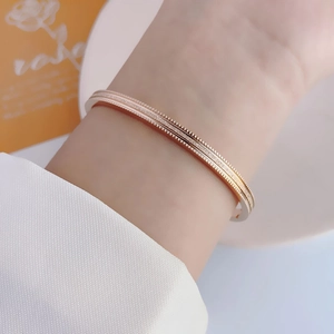 Detail of rose gold bangle featuring double beaded edges and frosted texture on wrist