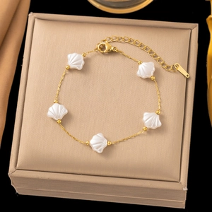Detail of a gold chain bracelet with white shell pendants on a jewelry display box