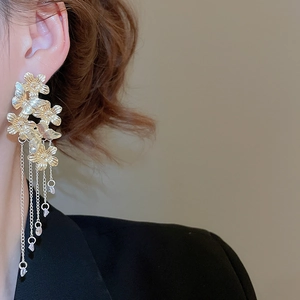 Detailed view of elegant gold floral tassel earrings with dangling crystals on a model