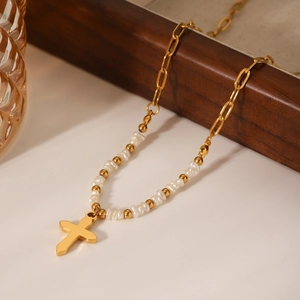 French vintage freshwater pearl necklace with gold cross pendant on a warm elegant background