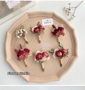 Detail showing 6-piece handmade corsages with red roses and eucalyptus on a beige tray