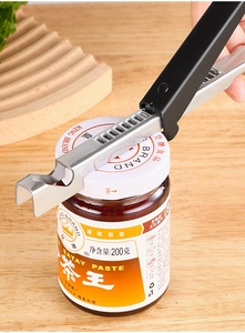 Detail showing a stainless steel manual can opener prying a metal lid off a glass jar