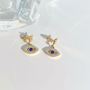 Golden Evil Eye stud earrings with blue crystals and star detail on white background