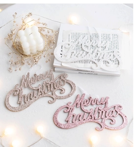 Close-up of glitter Merry Christmas hanging ornaments in white, gold, and rose pink