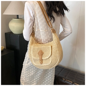 Detail of straw woven hobo bag with brown leather shoulder strap and decorative buckle