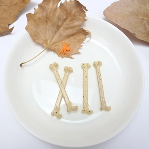 Mini Halloween skeletons with realistic spots on a tray with dry leaves and a spider toy