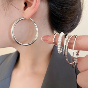Detail eines silbernen Creolen-Sets mit Perlen und gedrehten Metall-Designs an einem Modell