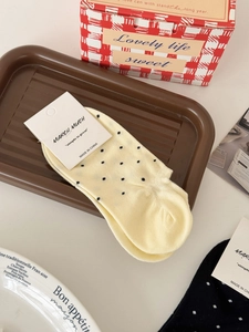 Socquettes jaunes à pois noirs sur un plateau avec des accessoires de décoration