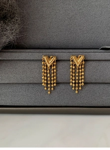 Macro shot of gold-plated V-shaped earrings with cascading beaded chain tassels detail