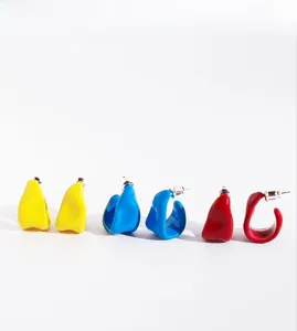 Detailed view of handmade enamel C-shaped hoop earrings in yellow, blue and red colors