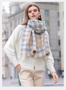Detail of soft grey and beige plaid scarf with decorative fringe on a street model