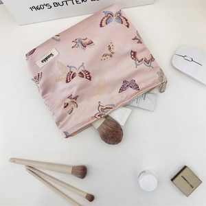 Detailed close-up of pink jacquard makeup bag with butterfly embroidery and metal zipper