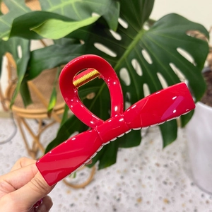 Close-up of a large red bow hair claw clip with a glossy finish and gold metal spring