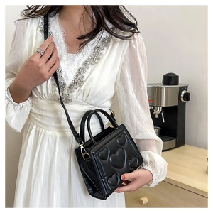 Détail du sac à main noir en similicuir avec motif cœurs et bandoulière réglable