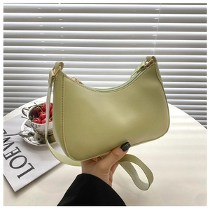 Detail of avocado green leather baguette bag with gold zipper and smooth texture