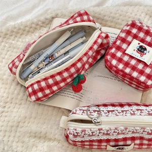 Detailed view of red plaid plush cosmetic bags with lace and cherry charm accessories
