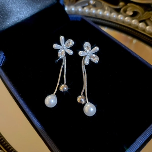 Close-up of pearl flower tassel earrings with crystals on dark velvet jewelry box