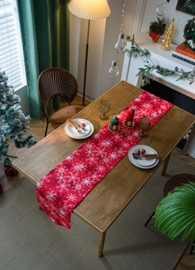Close-up of a festive red Christmas table runner featuring white snowflake patterns
