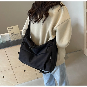 Detail view of a large black crossbody tote bag with multi-pockets and adjustable strap
