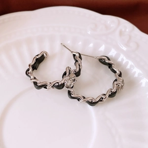 Detail view of C-shaped earrings with black leather chain and a square crystal inlay