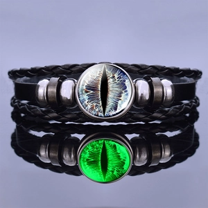 Macro detail of leather bracelet with glowing dragon eye pendant reflecting on surface