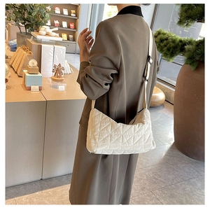 Detail of a beige quilted crescent shoulder bag with elegant diamond stitch patterns