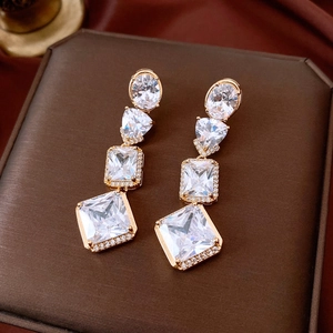 Close-up of vintage golden drop earrings with geometric zircons on luxury jewelry box