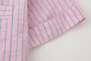 Détail des rayures verticales roses sur tissu avec couture de poche et revers de manche