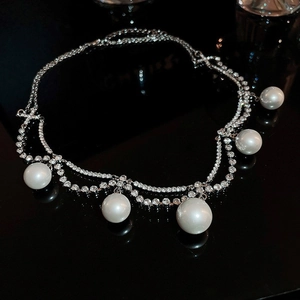 Macro detail of luxury double-layer pearl necklace with pavé rhinestones on black glass