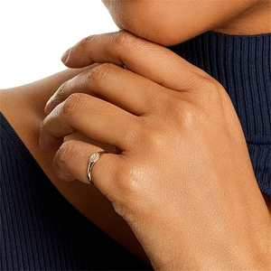 Macro shot of a golden minimalist pinky ring with small crystals on a navy sweater background