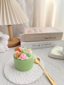 Detailed view of matcha cake scented candle with pink berries on a lace coaster
