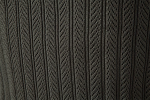 Detail of dark green knit fabric with vertical stripes and hollow diamond patterns