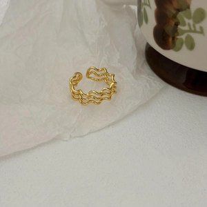 Minimalist three-layer wave opening ring in gold finish on white textured paper
