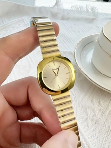 Detailed close-up of a square gold quartz watch featuring a metallic elastic expansion band