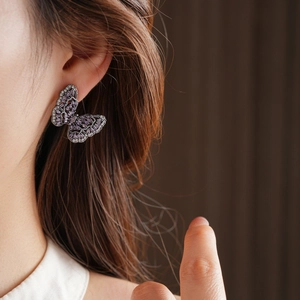 Detail of purple butterfly earrings with micro-inlaid cubic zirconia on a female ear