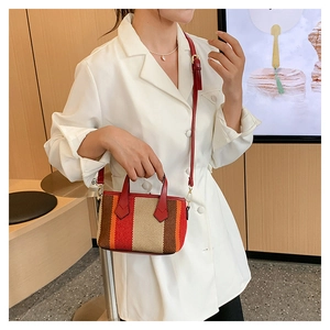 Fashionable striped canvas crossbody bag with red straps shown in a lifestyle street style