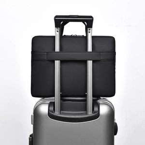 Waterproof laptop bag shown mounted on silver suitcase handle via its back luggage strap