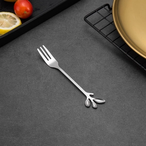 Close-up of creative silver leaf handle stainless steel fruit fork on a textured stone surface