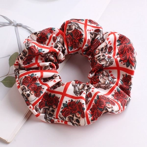 Detail of satin scrunchie featuring vintage red roses and skull prints on cream fabric