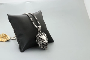 Detailed close-up of a silver lion head pendant on a sturdy box chain necklace