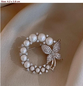 Detail of a butterfly and pearl wreath brooch measuring 4.2x3.8cm with golden finish