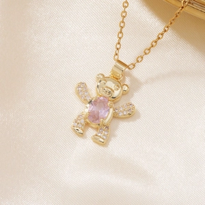 Macro view of golden bear pendant with pink gemstone and pavé zircon settings