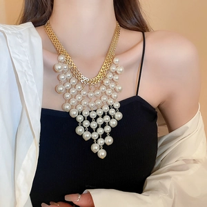 Collier doré extravagant avec pampilles de perles blanches porté par un mannequin