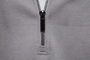 Detailed close-up of smooth black metal zipper on premium grey knitted fabric sweater