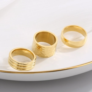 Detailweergave van drie 18K vergulde titanium ringen met gehamerde en gegroefde texturen