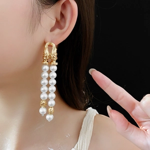 Close-up of vintage style gold drop earrings with double layered faux pearls on a model